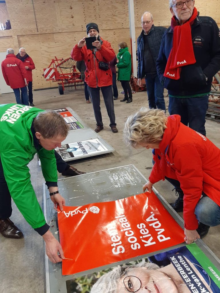 Margo van Enck en Pouwel Inberg plakken samen de posters van de PvdA en GroenLinks