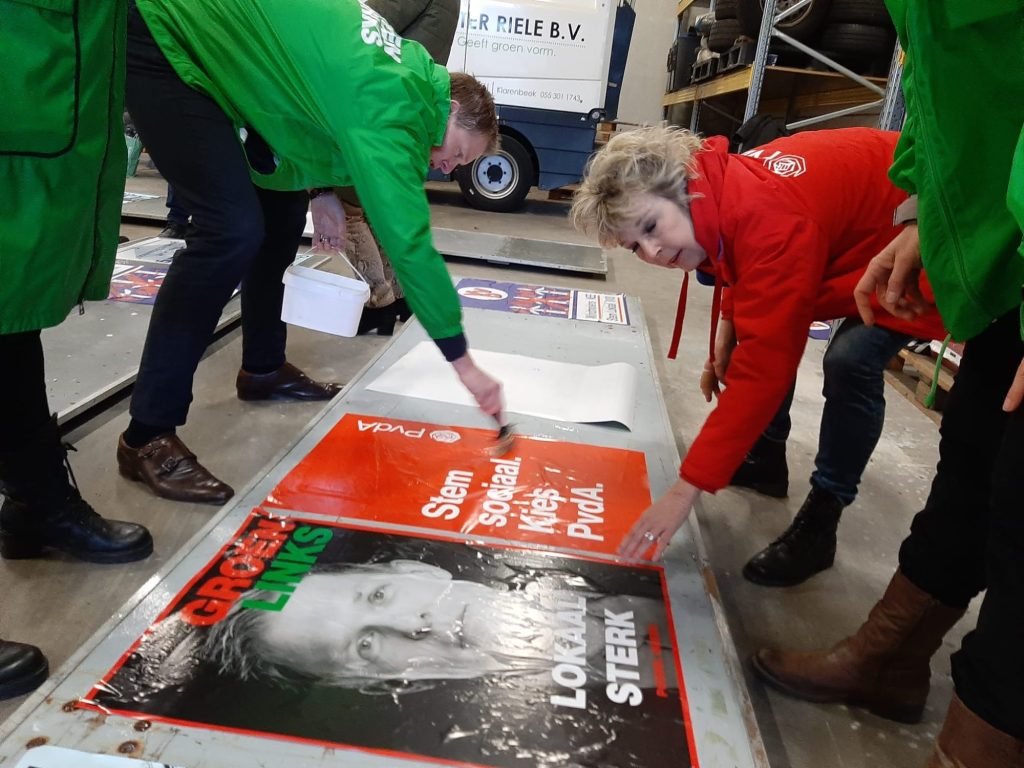Margo van Enck en Pouwel Inberg plakken samen de posters van de PvdA en GroenLinks