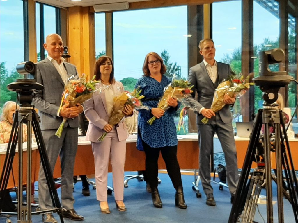 De wethouders Steven van de Graaf, Ingrid Timmer, Annika van Klinken en Pouwel Inberg met elk een bos bloemen in hun handen.