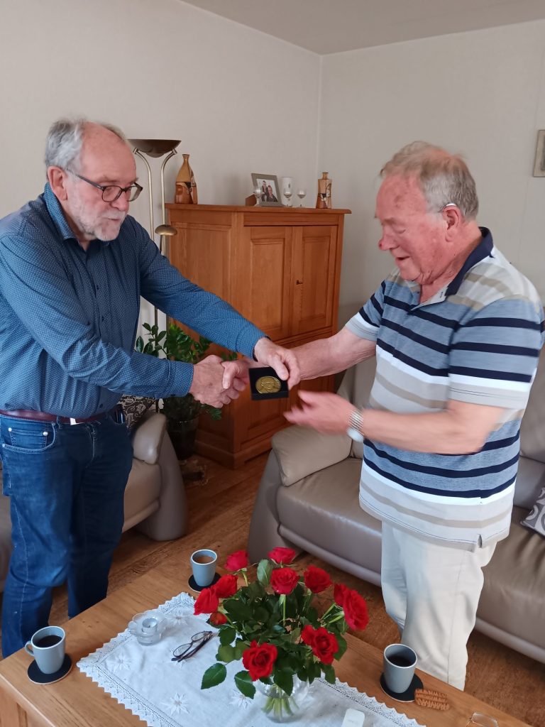 Voorzitter Fred Janssen overhandigt de jubileumplaquette aan Geert Gierman.